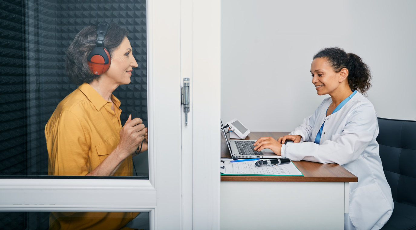 audiologist with lady in sound proof booth